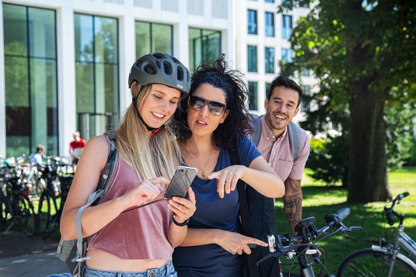 Radfahrerinnen schauen gemeinsam auf ein Smartphone.