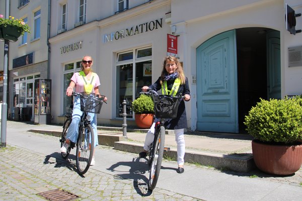 zwei Frauen auf Fahrrädern vor der Tourist-Information